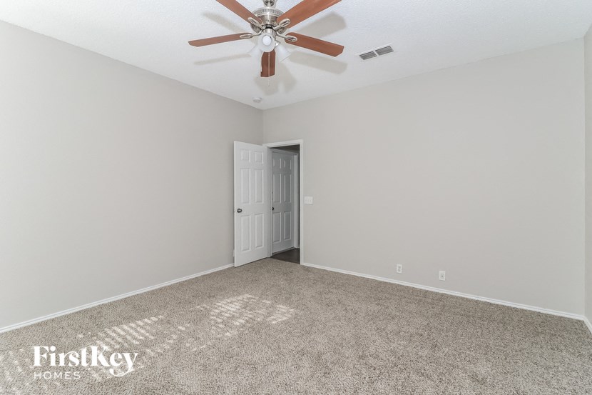the spacious living room with ceiling fan and carpet