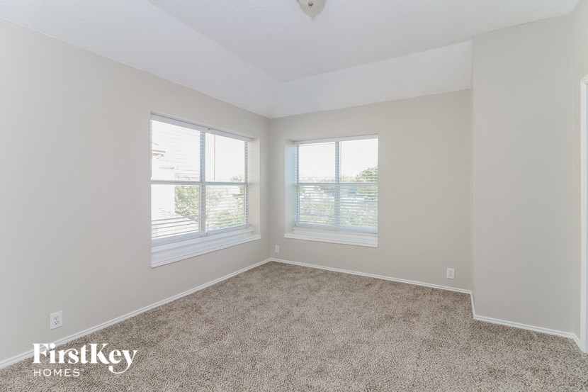 the living room of an empty house with carpet and three windows