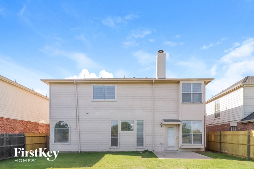 the front of a white house with a yard and a blue sky