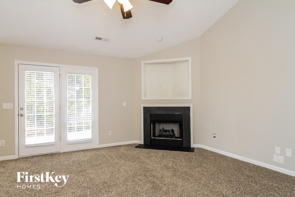 A living room with a fireplace and a ceiling fan.