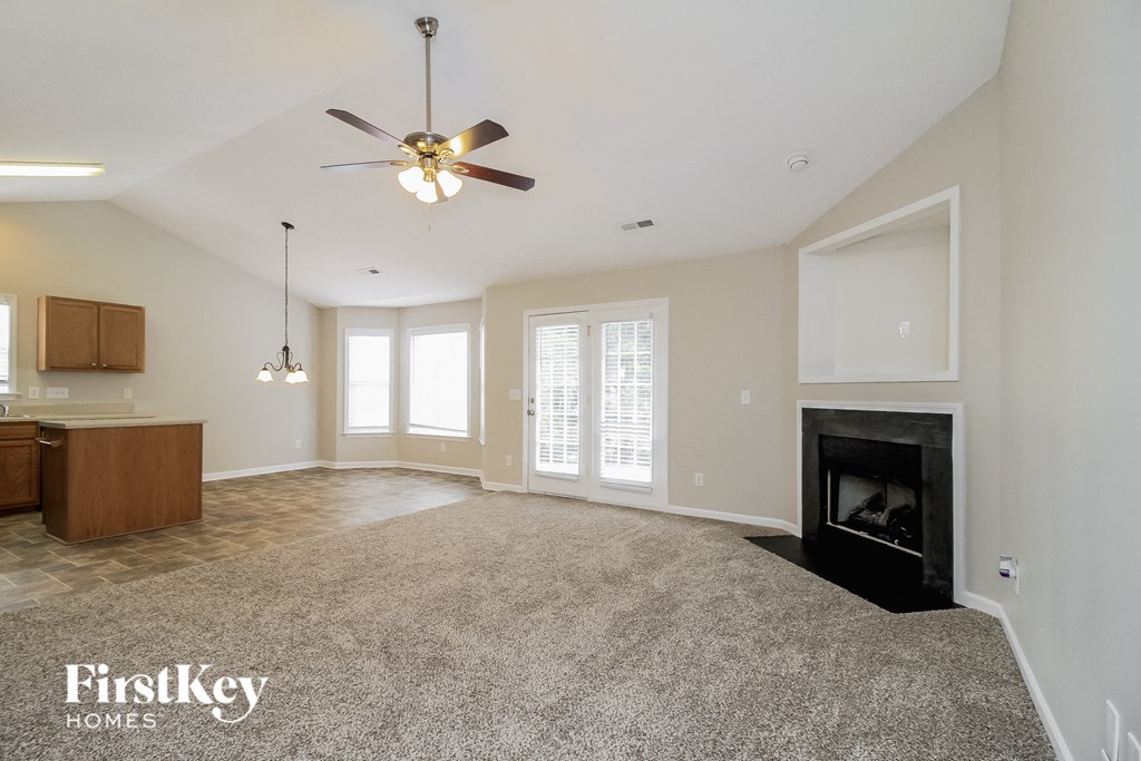 A spacious living room with a fireplace and a ceiling fan.