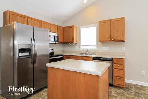 A kitchen with wooden cabinets and a stainless steel refrigerator.