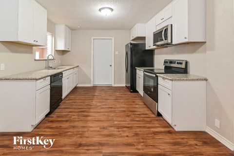 A kitchen with white cabinets and a wooden floor.