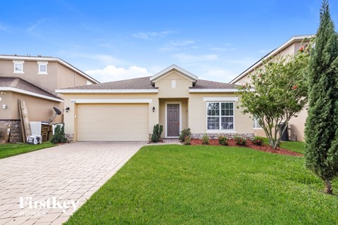 a beige house with a lawn and a driveway