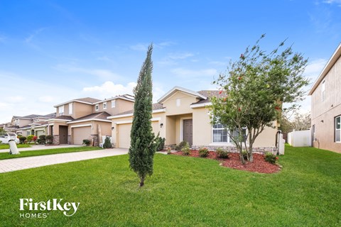 a house with a yard and trees in front of it