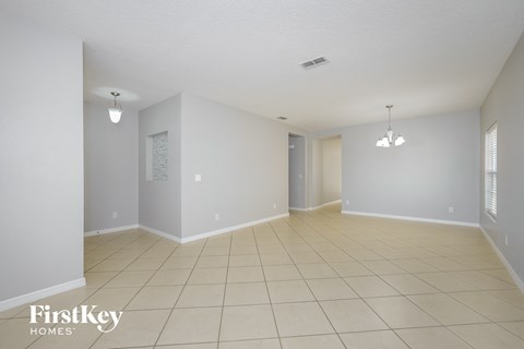 a spacious living room with tiled floors and white walls
