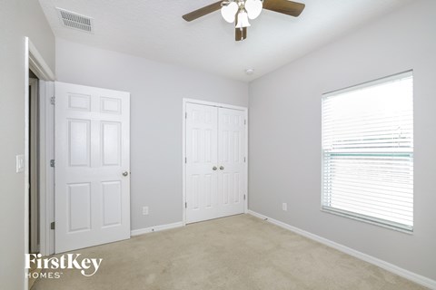 a bedroom with two closets and a ceiling fan and a window