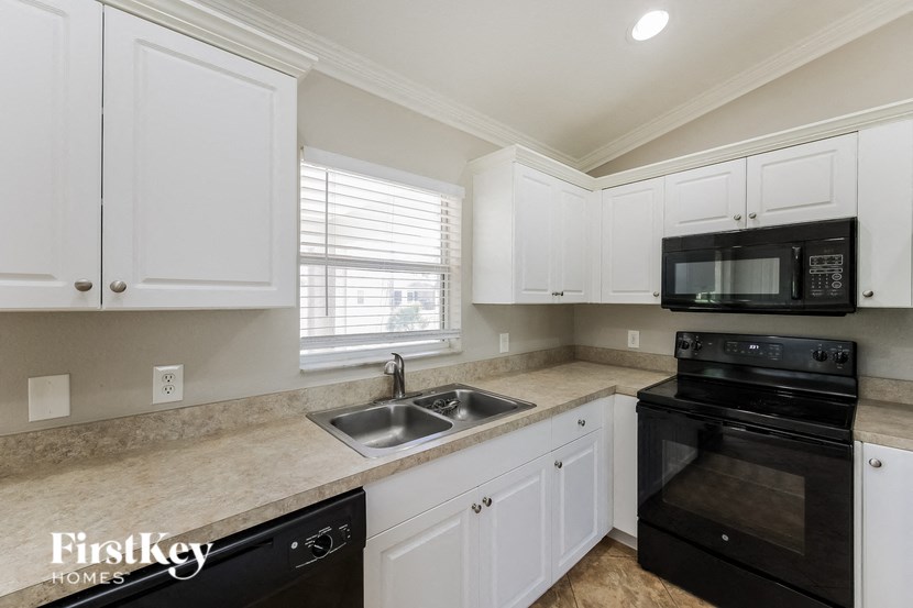 A kitchen with white cabinets and black appliances.