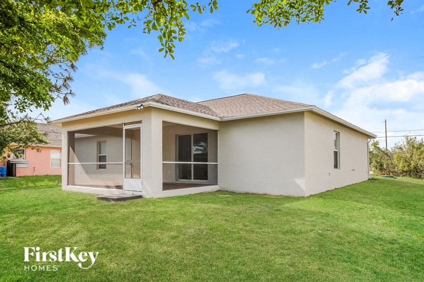 A house with a brown roof and a white exterior is surrounded by a grassy lawn.