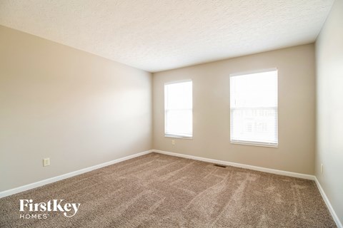 a bedroom with carpet and two windows