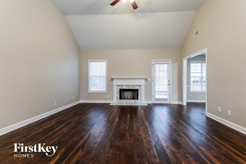 A spacious room with a fireplace and wood flooring.