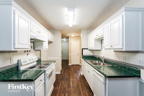 A kitchen with white cabinets and green countertops.