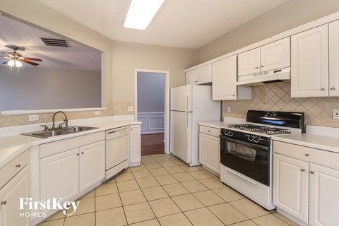 A kitchen with white cabinets and appliances.