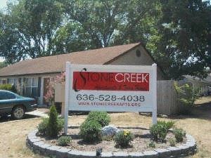 a sign for stone creek in front of a house