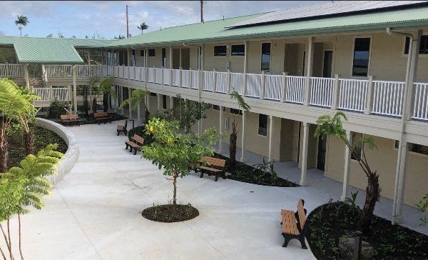 A courtyard with benches and trees in front of a building.