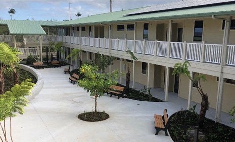 A courtyard with benches and trees in front of a building.