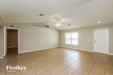 A spacious room with tile flooring and a ceiling fan.