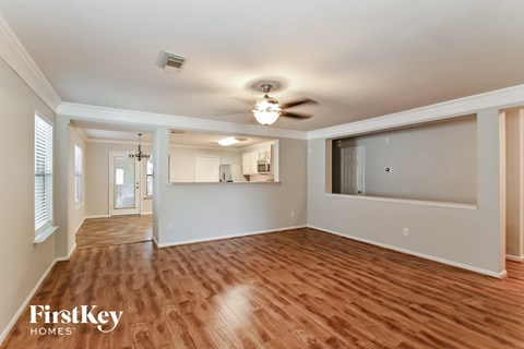 A spacious room with wooden floors and a ceiling fan.