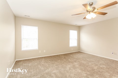 a living room with carpet and a ceiling fan