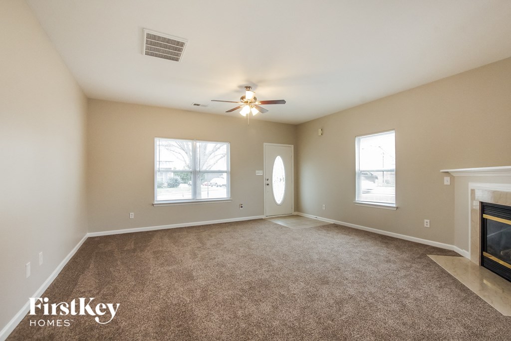 an empty living room with a ceiling fan and a fireplace
