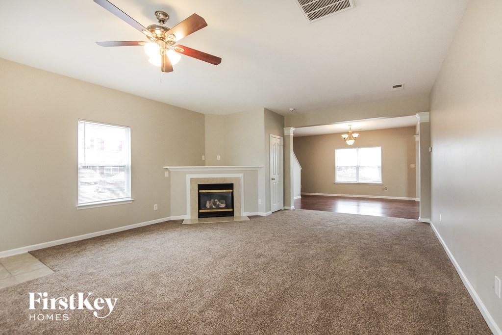 an empty living room with a ceiling fan and a fireplace