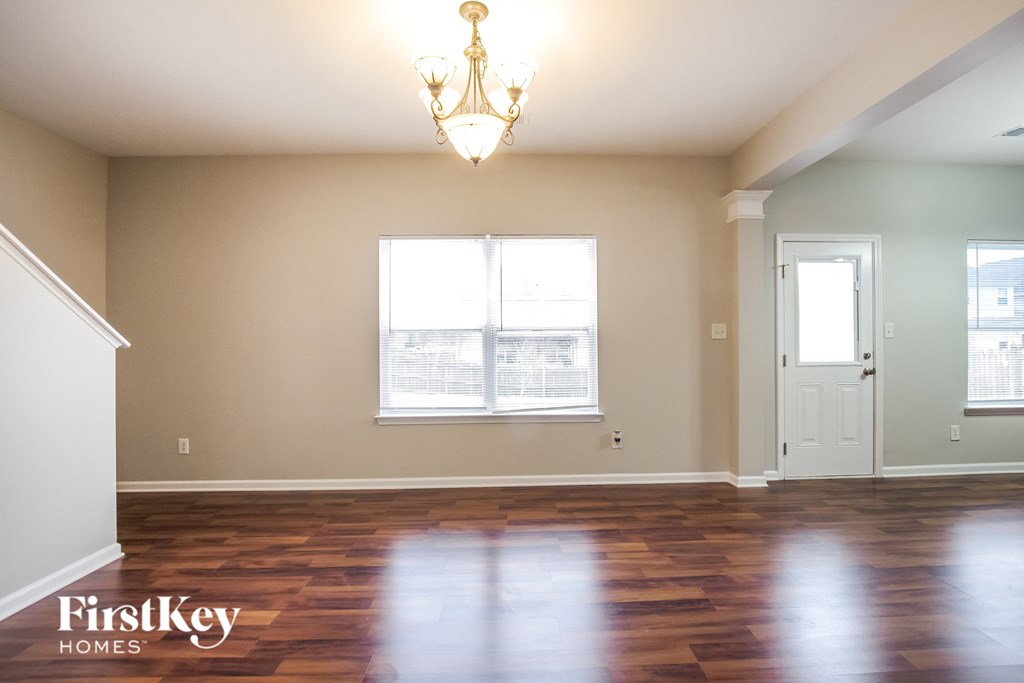 an empty living room with wood floors and a chandelier