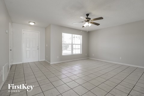 an empty living room with a ceiling fan and tiled floor