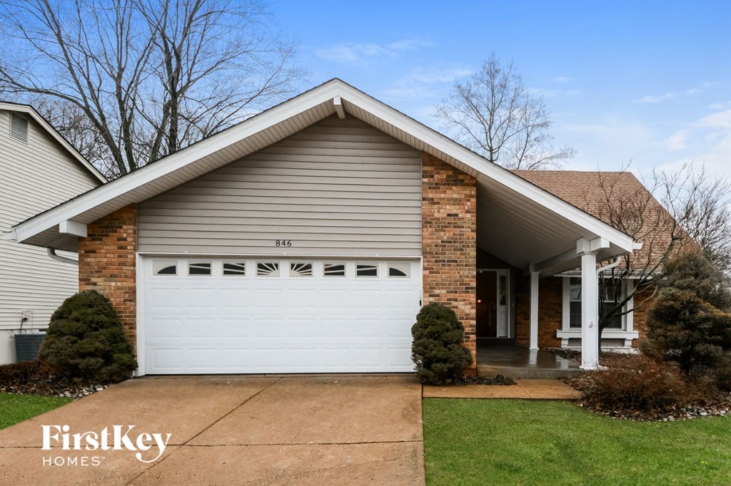A house with a garage door and a brick chimney.