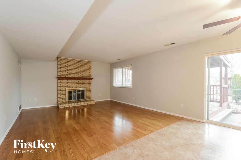 A spacious room with a fireplace and a fan.