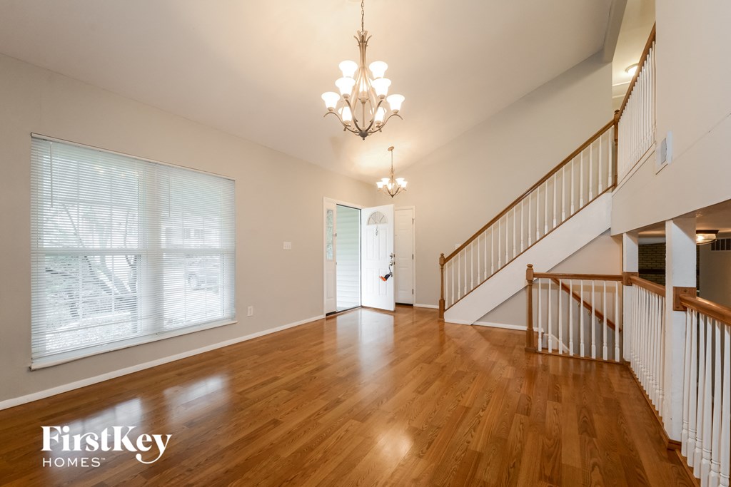 A spacious room with wooden floors and a staircase.