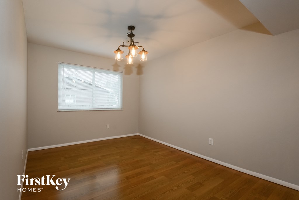 A room with wooden floors and a chandelier hanging from the ceiling.