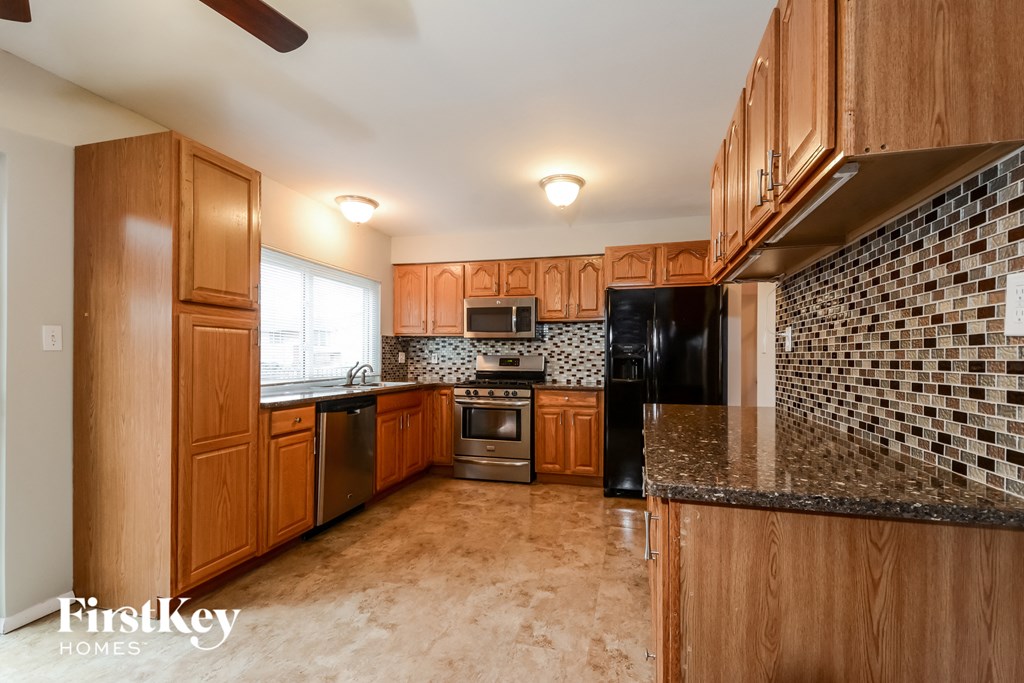 A kitchen with wooden cabinets and a black refrigerator.