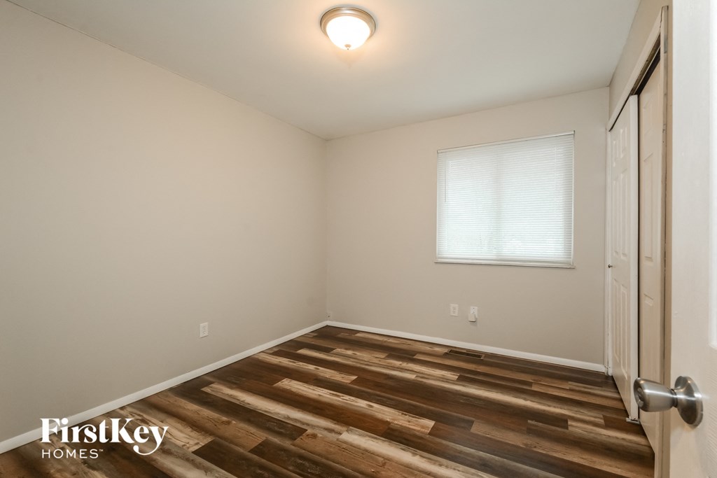 A room with wooden flooring and a door on the right side.