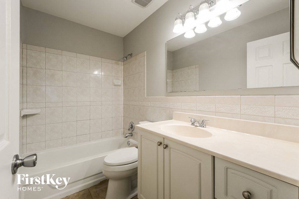 A bathroom with a white toilet, sink, and a mirror.