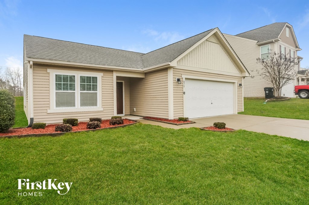 A house with a garage and a red truck in the background.
