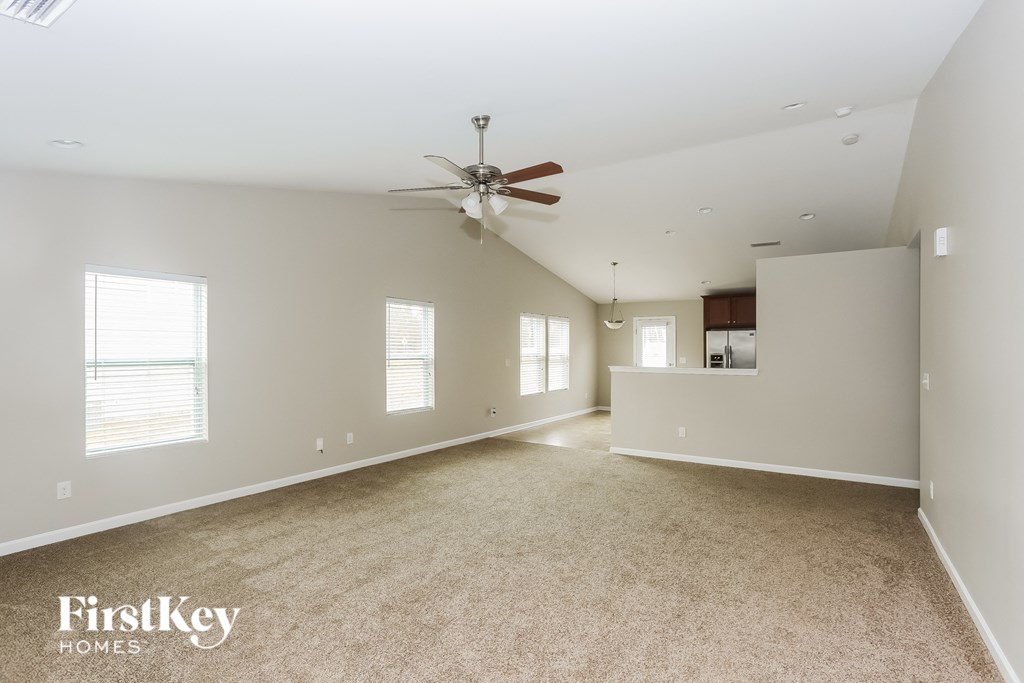 A spacious room with a ceiling fan and carpeted floor.