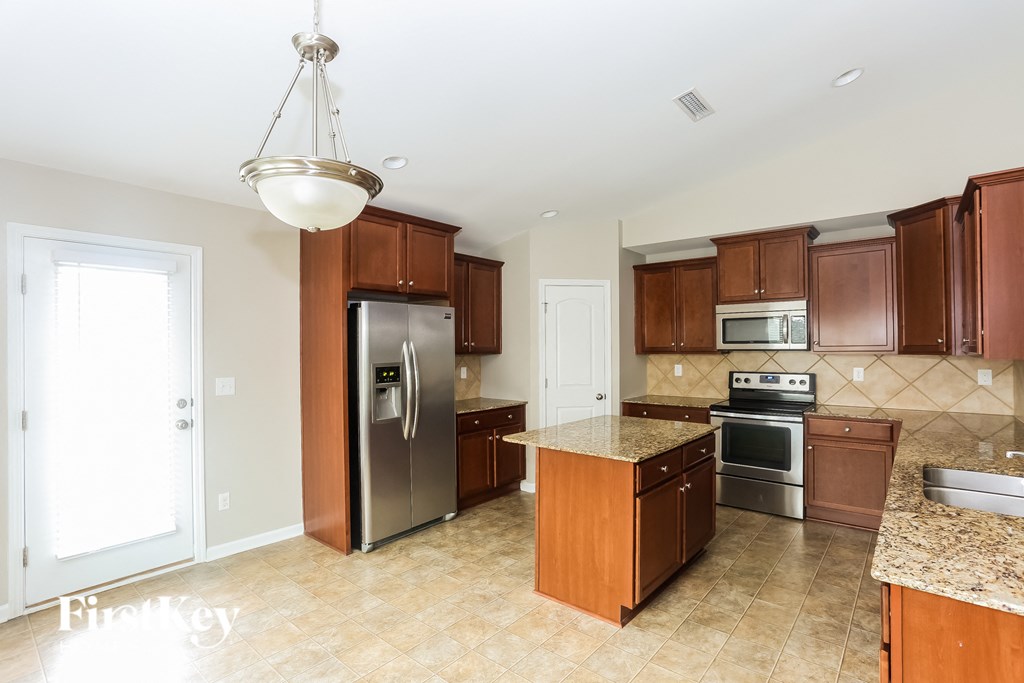 A kitchen with a refrigerator, oven, and microwave.