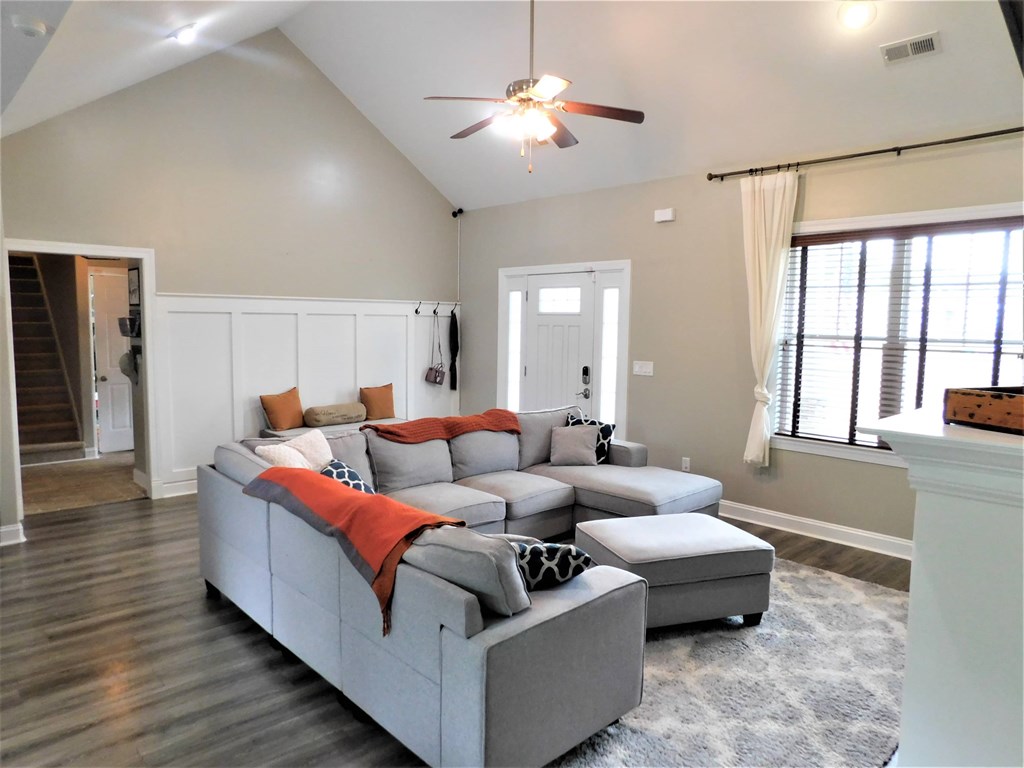 A living room with a grey couch and a ceiling fan.