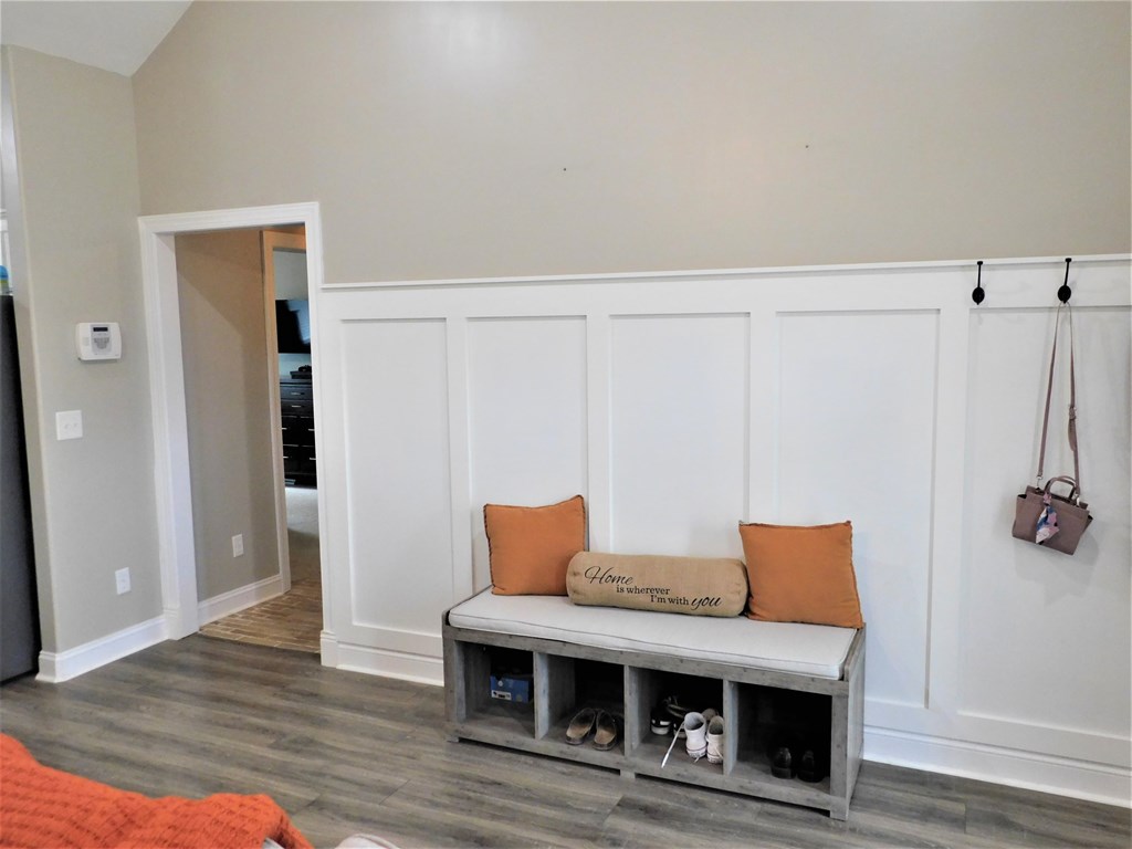 A bench with two pillows and a sign that says "Home Sweet Home" is in the corner of a room.