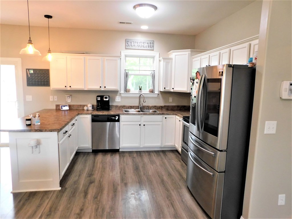 A kitchen with white cabinets and a wooden floor.