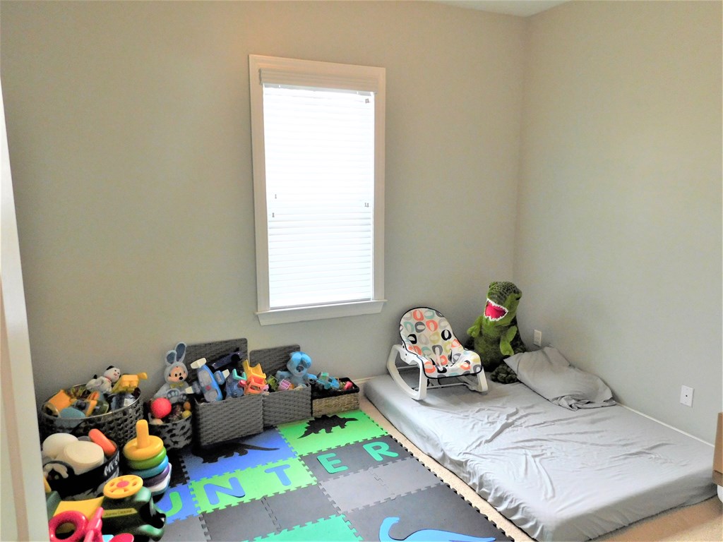A child's bedroom with a bed, chair, and toys.