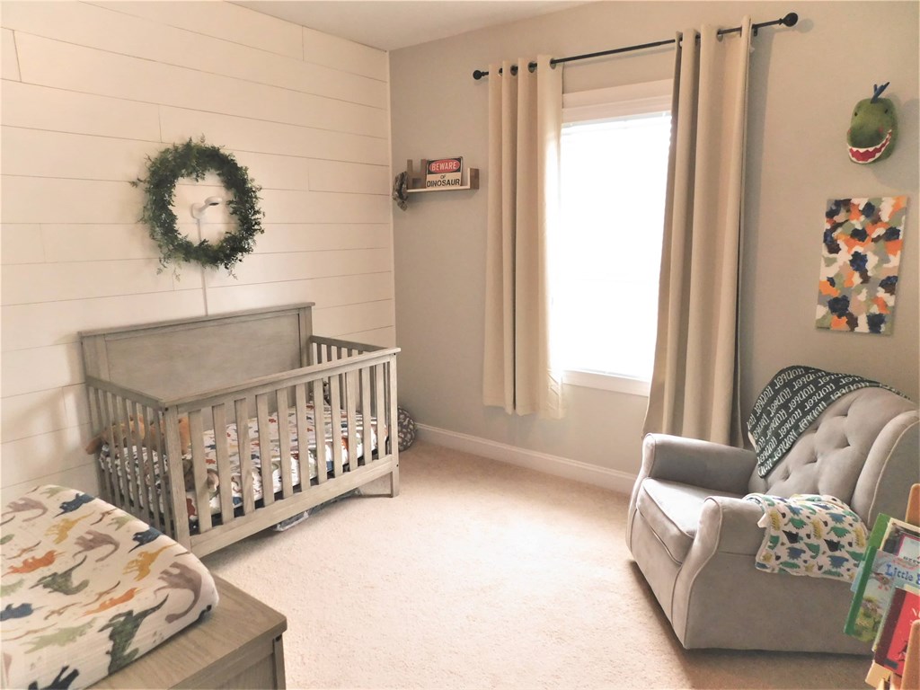 A baby's room with a crib, chair, and a wreath on the wall.