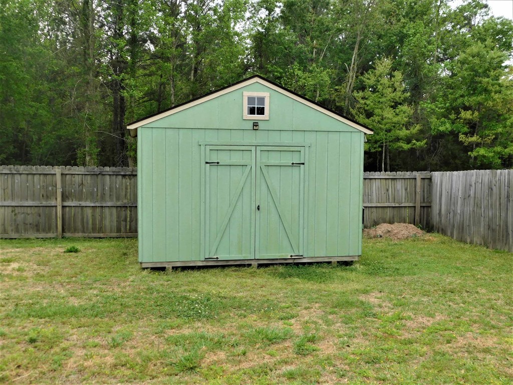 A green shed with a brown fence in the background.
