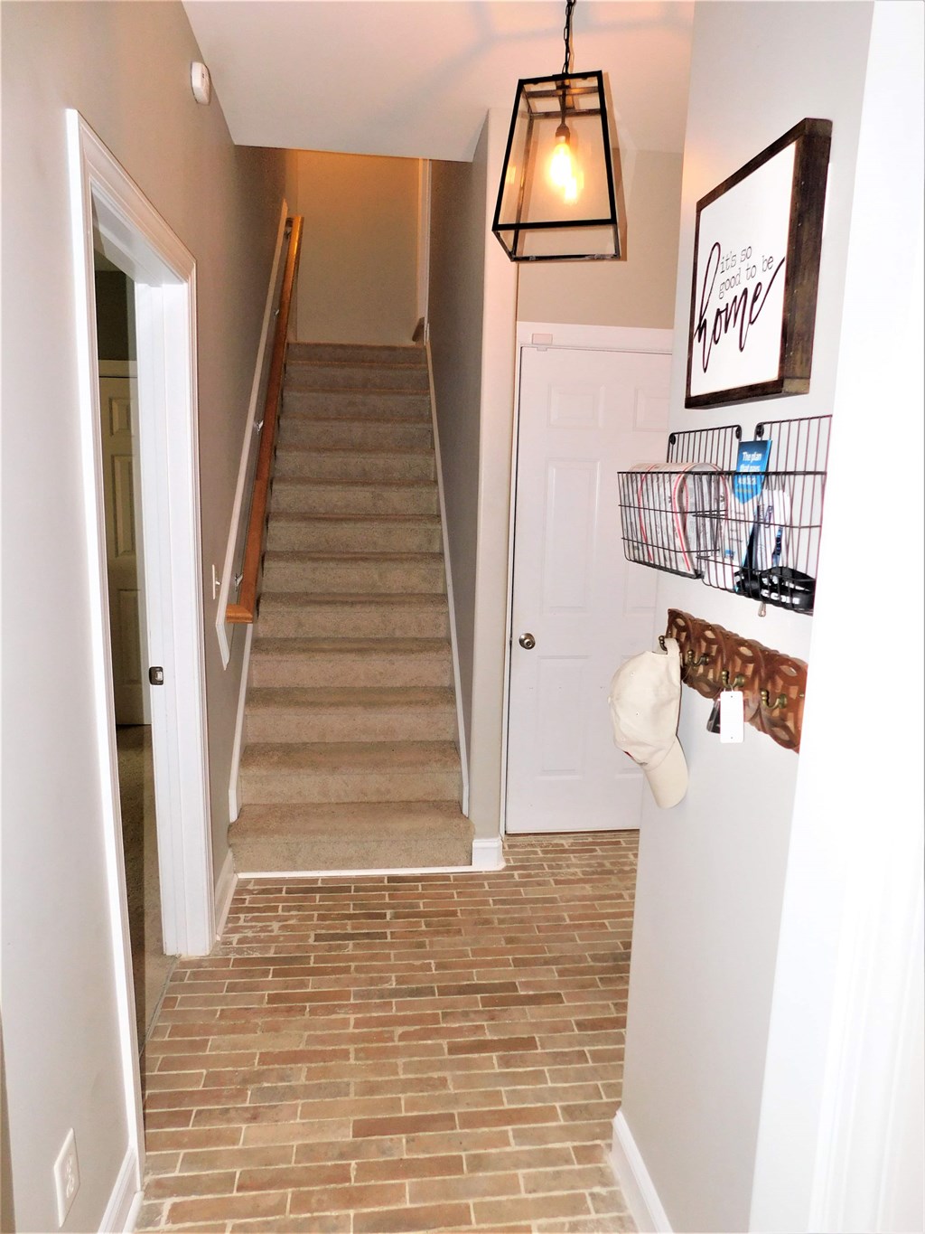 A hallway with a staircase and a light hanging from the ceiling.