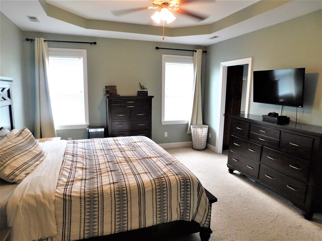 A bedroom with a bed, dresser, and ceiling fan.