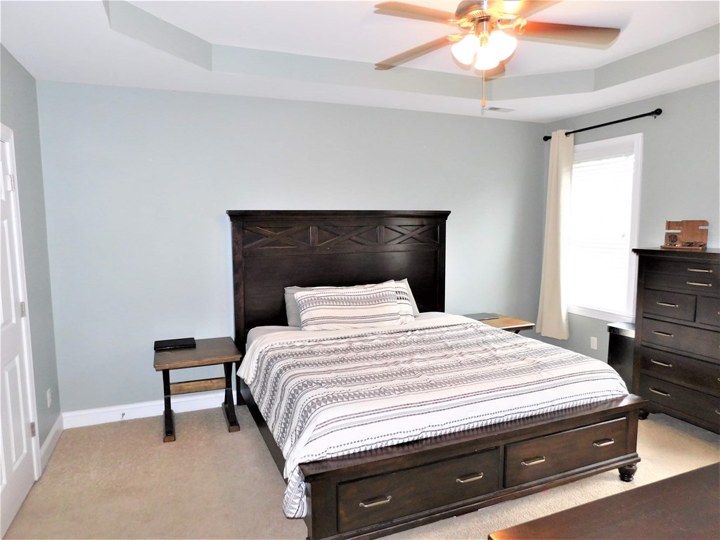 A bedroom with a large bed and a ceiling fan.