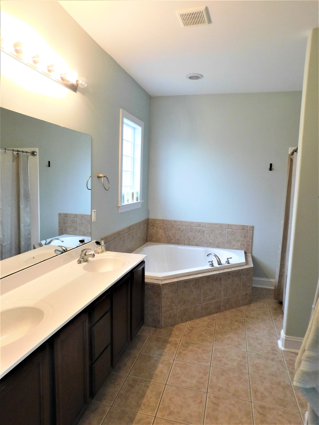 A bathroom with a large tub and double sinks.