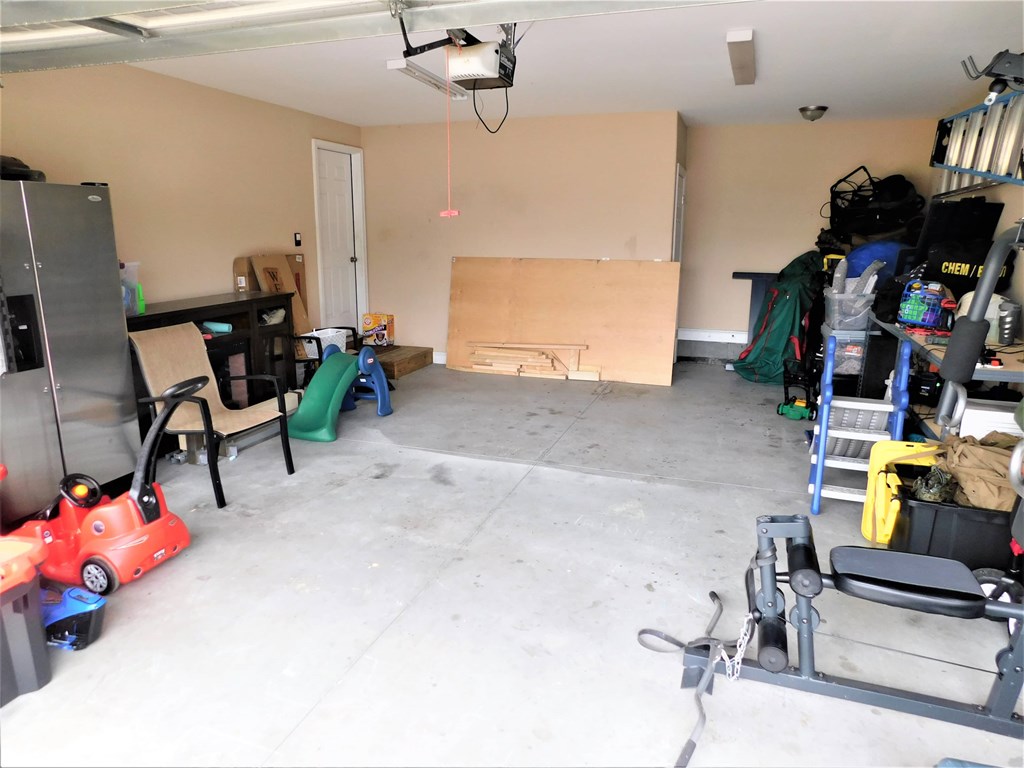 A garage with a red lawn mower and a green step stool.