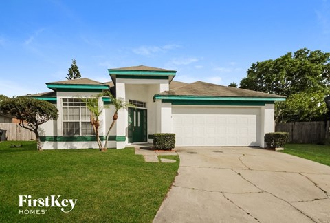 a white and green house with a driveway and a garage door