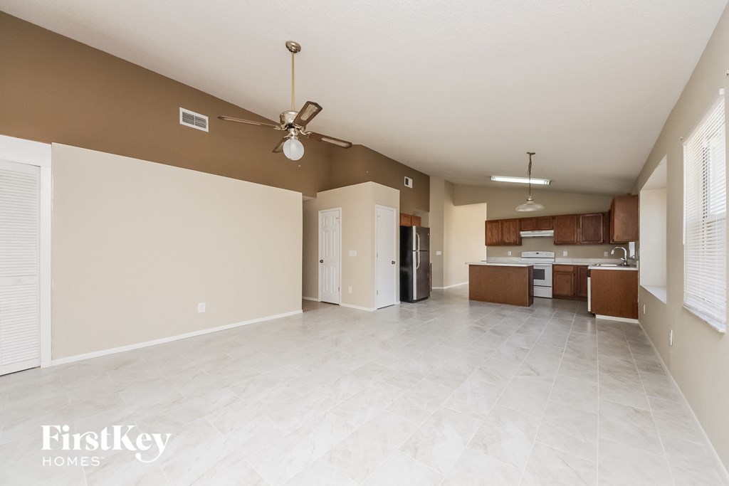 an empty living room and kitchen with a ceiling fan